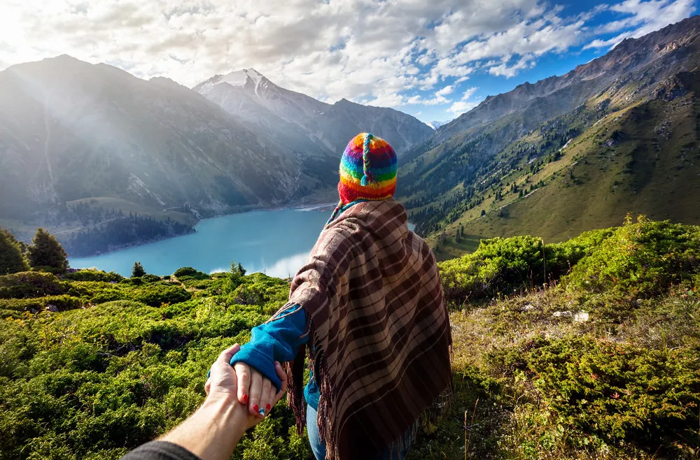 Tourist Woman In Rainbow Hat And Brown Poncho Holding Man